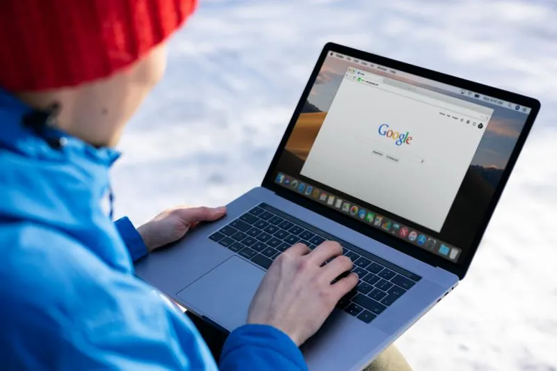 Person typing a search into Google on a laptop
